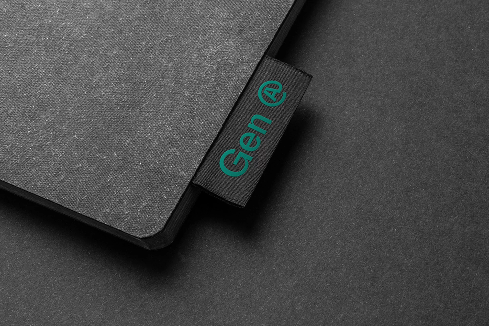 Close-up of a textured gray surface with a black label displaying the text 'Gen @' in teal, contrasted against a dark background.