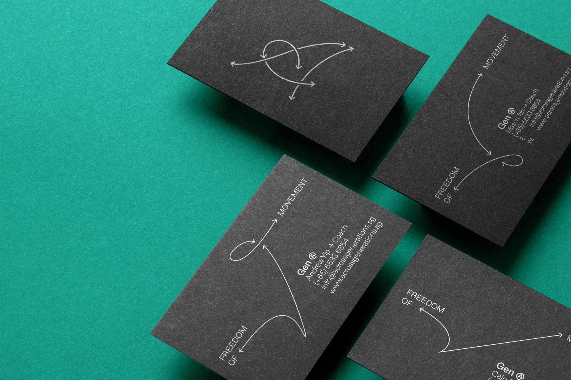 Four dark gray business cards are displayed on a vibrant teal background, showcasing minimalistic designs with white text and directional graphics.