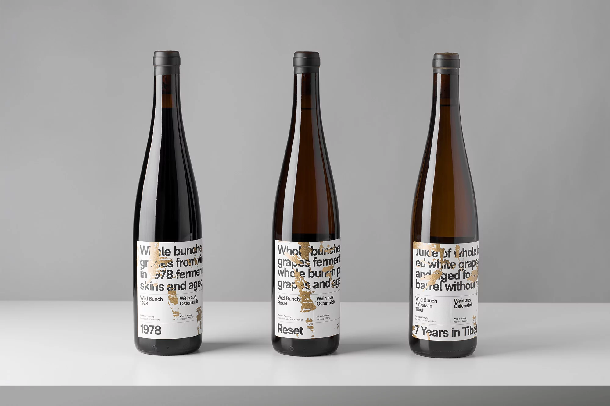 Three wine bottles with labels featuring the text 'Whole bunches grapes fermented' and minimal design, set against a neutral background.