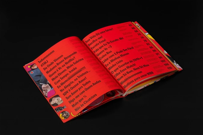 Open magazine displaying content in Portuguese with red pages and various images on a black background, magazine flat lay.