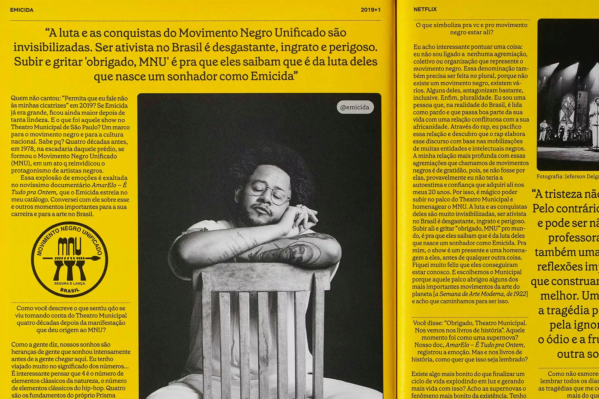 Black and white photo of Emicida with his eyes closed, sitting in a chair with newspaper clippings surrounding him.