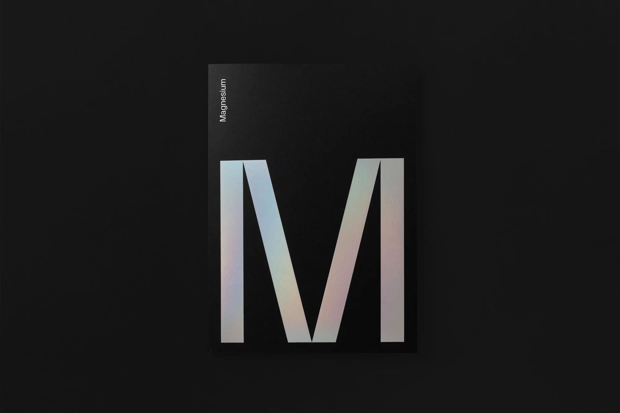 Abstract metallic letter M graphic design. Modern minimalist concept with iridescent hues, geometric shapes, and dark studio backdrop.
