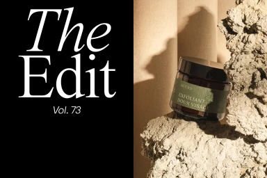 Exfoliant jar product resting on rough textured stone against a neutral backdrop with bold typographic text on the left.