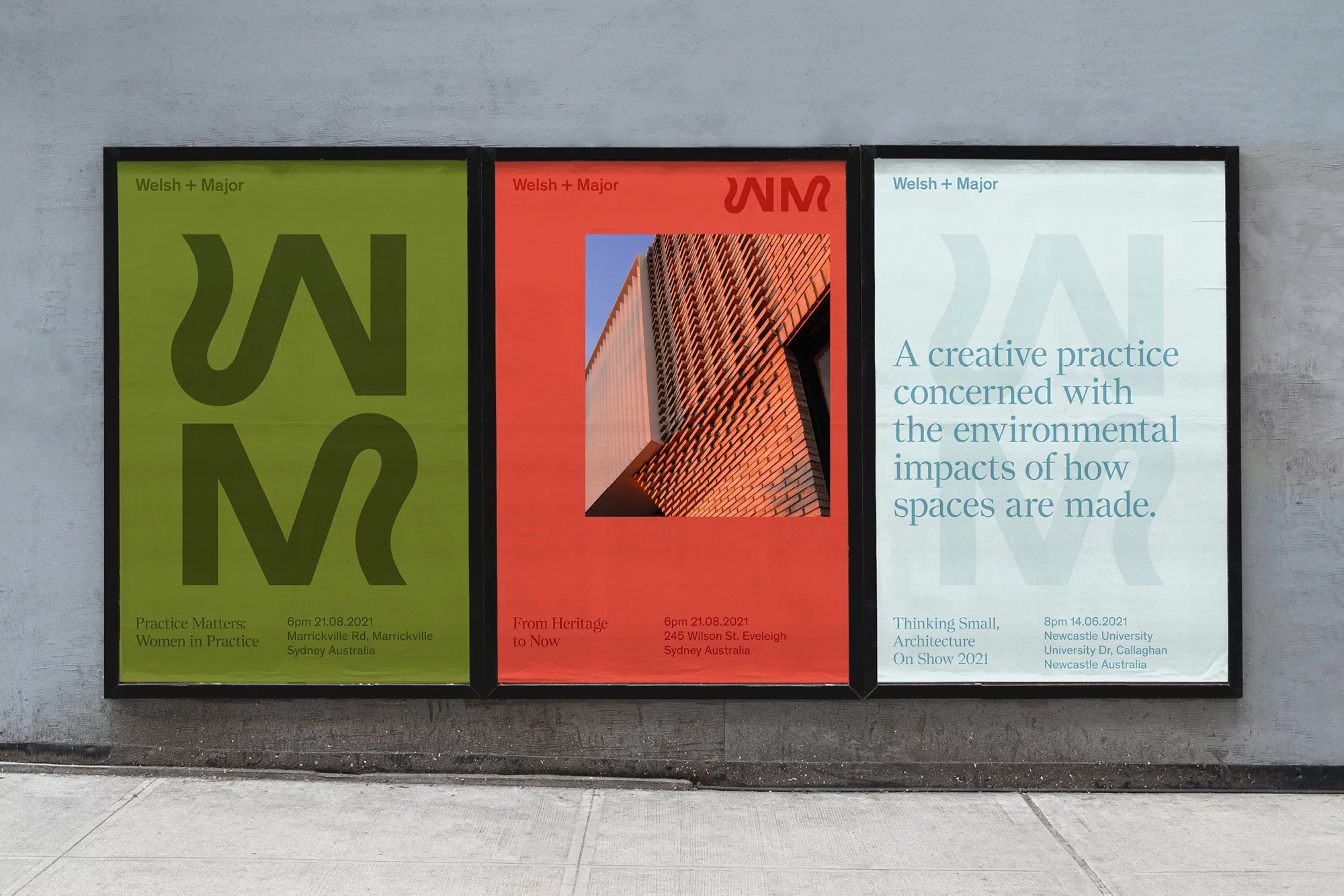 Three framed posters side-by-side exhibit Welsh + Major architecture designs, featuring typography and architectural visuals in a gallery-like setting.
