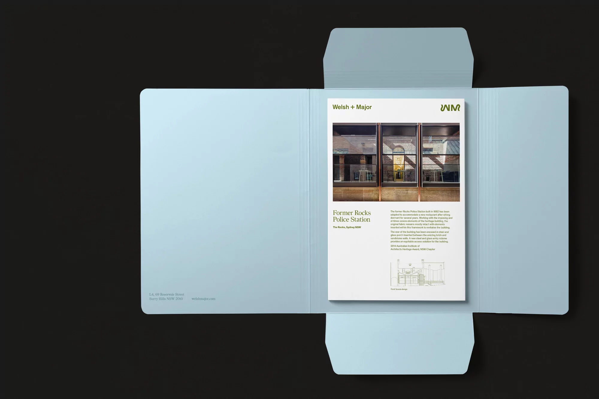 Architectural presentation of the 'Former Rocks Police Station' project, featuring a booklet inside an opened, light blue folder against a dark background.