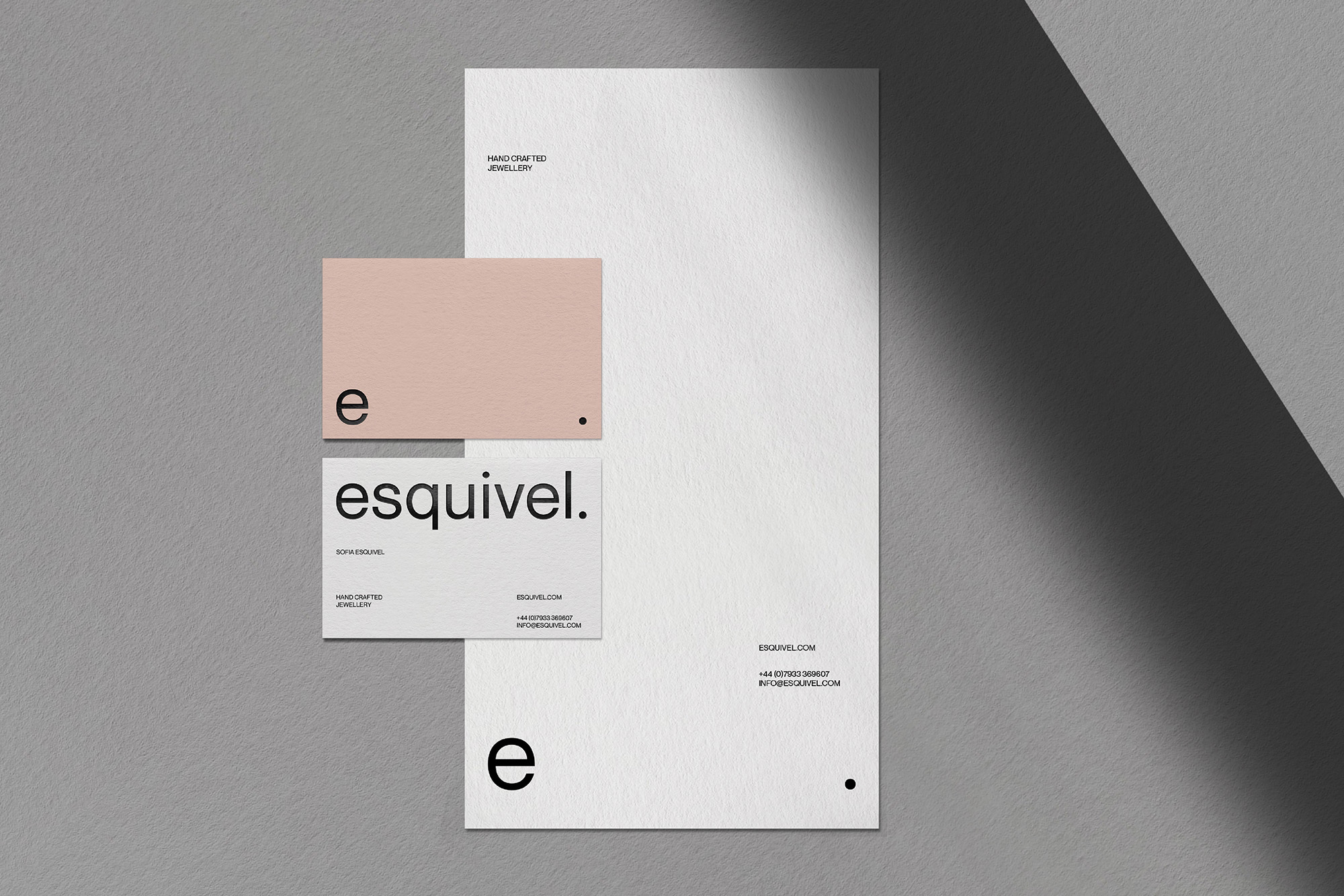 Minimalist stationery mockup featuring a rectangular card, business cards, and letterhead in white and peach on a gray surface.