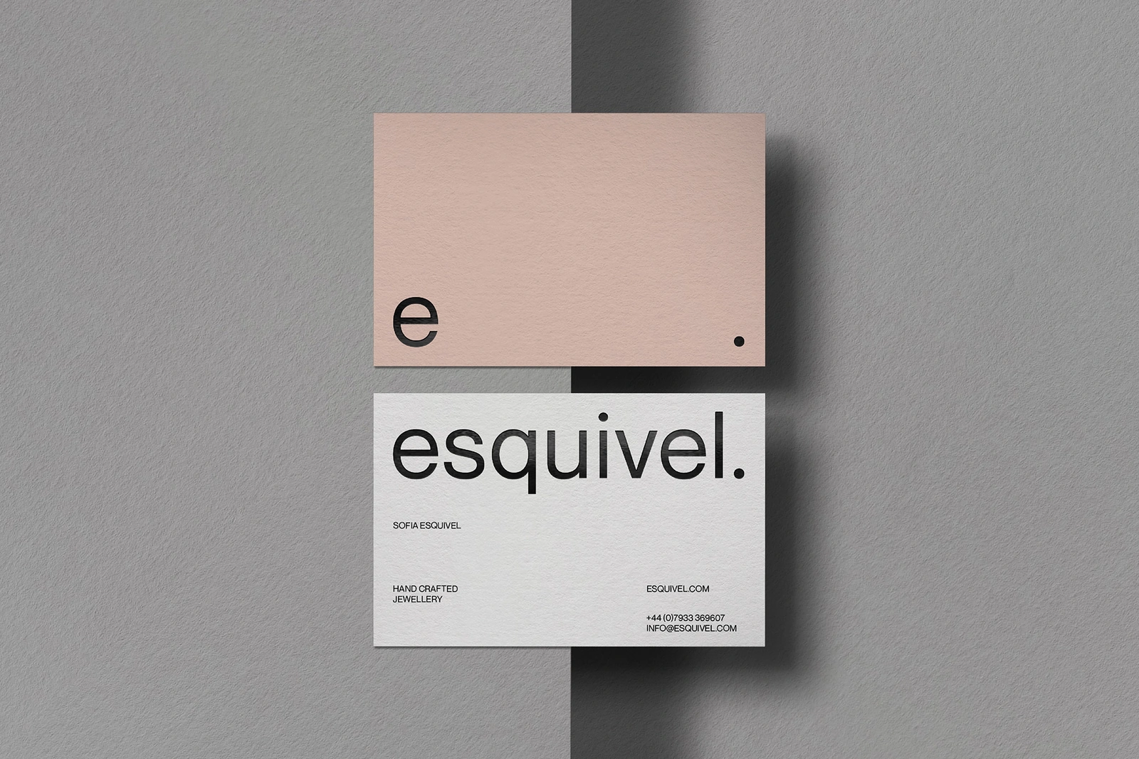 Two business cards with minimal typography displayed on a textured grey background surface