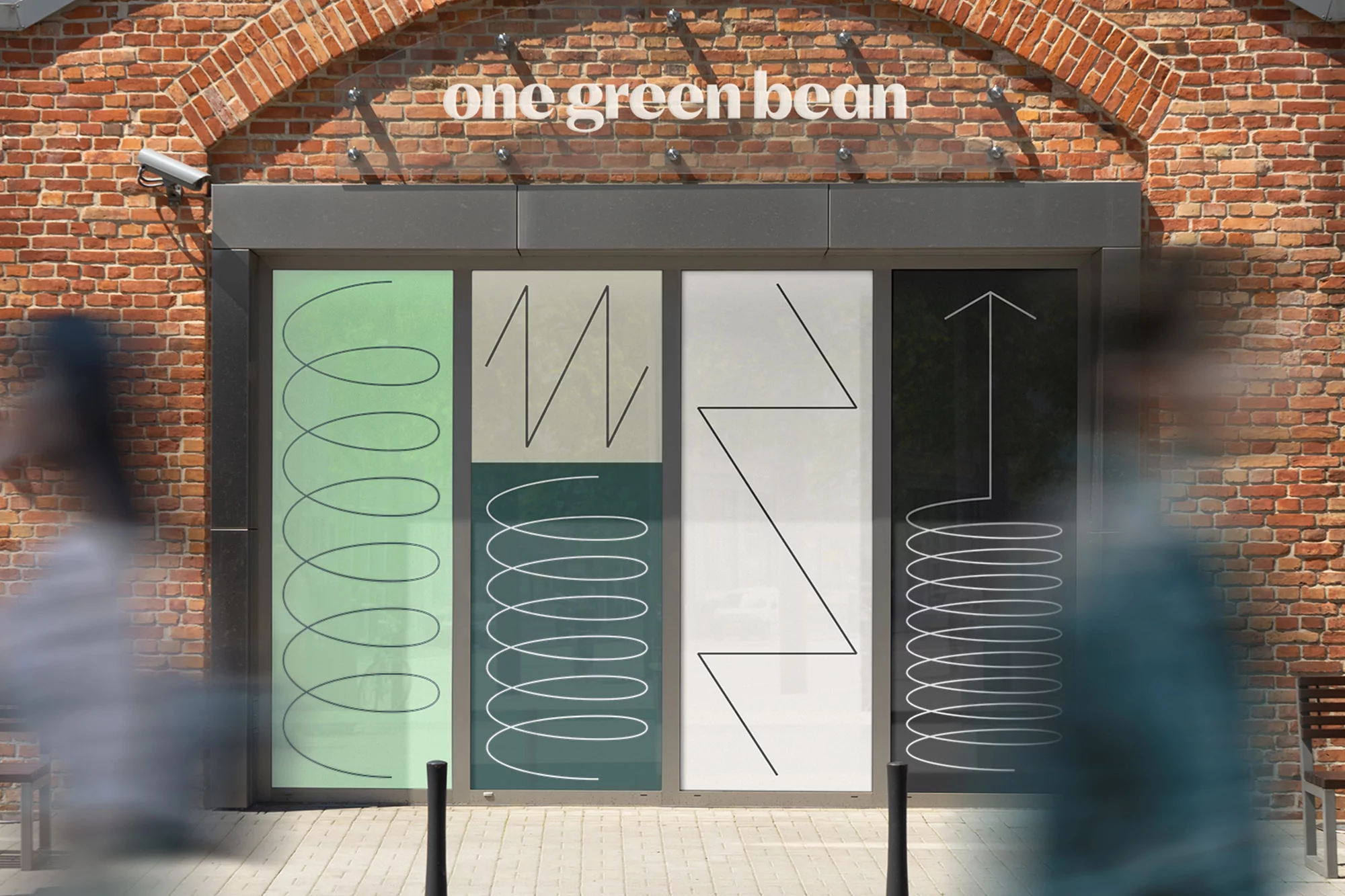Building facade with brick wall and glass entrance featuring graphic art with geometric patterns and the words 'one green bean'.