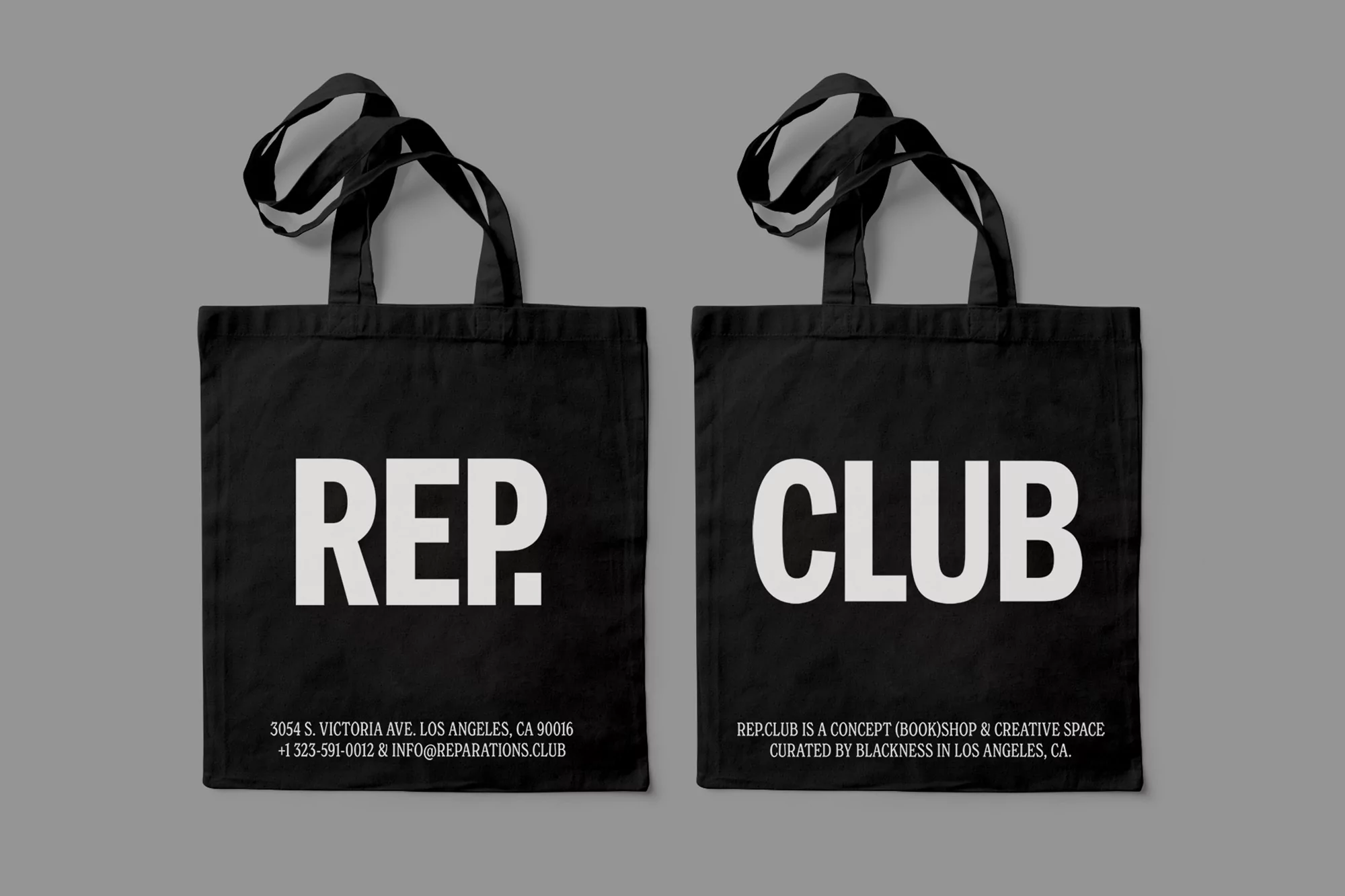 Two black tote bags featuring white text 'REP' and 'CLUB' with address and website details, set against a neutral grey background.