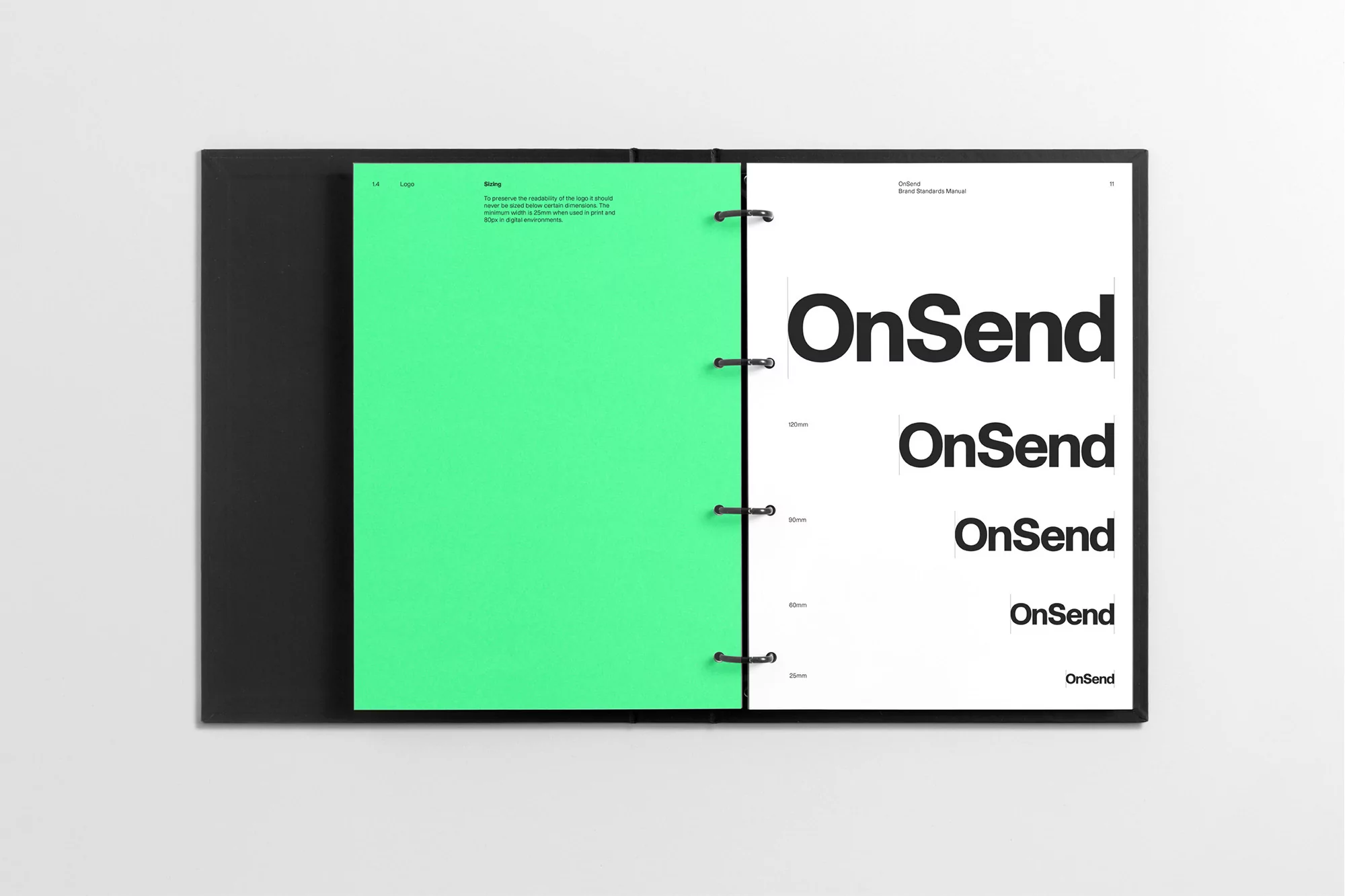 Open brand standards manual binder displaying typography guidelines on a white page and a bright green divider sheet
