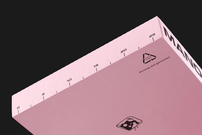 Close-up view of a pink box, angled perspective, featuring black measurement lines and recycling symbols against a black background.