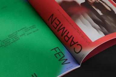 An open magazine spread featuring bold typography on vibrant green and red pages, photographed from an angle.