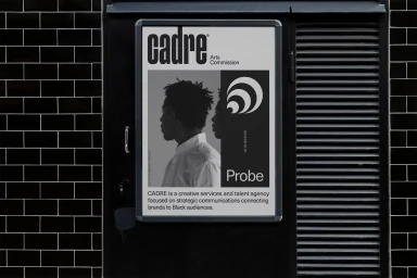 Black and white poster featuring typography and a profile portrait mounted on a dark tiled wall outdoors.