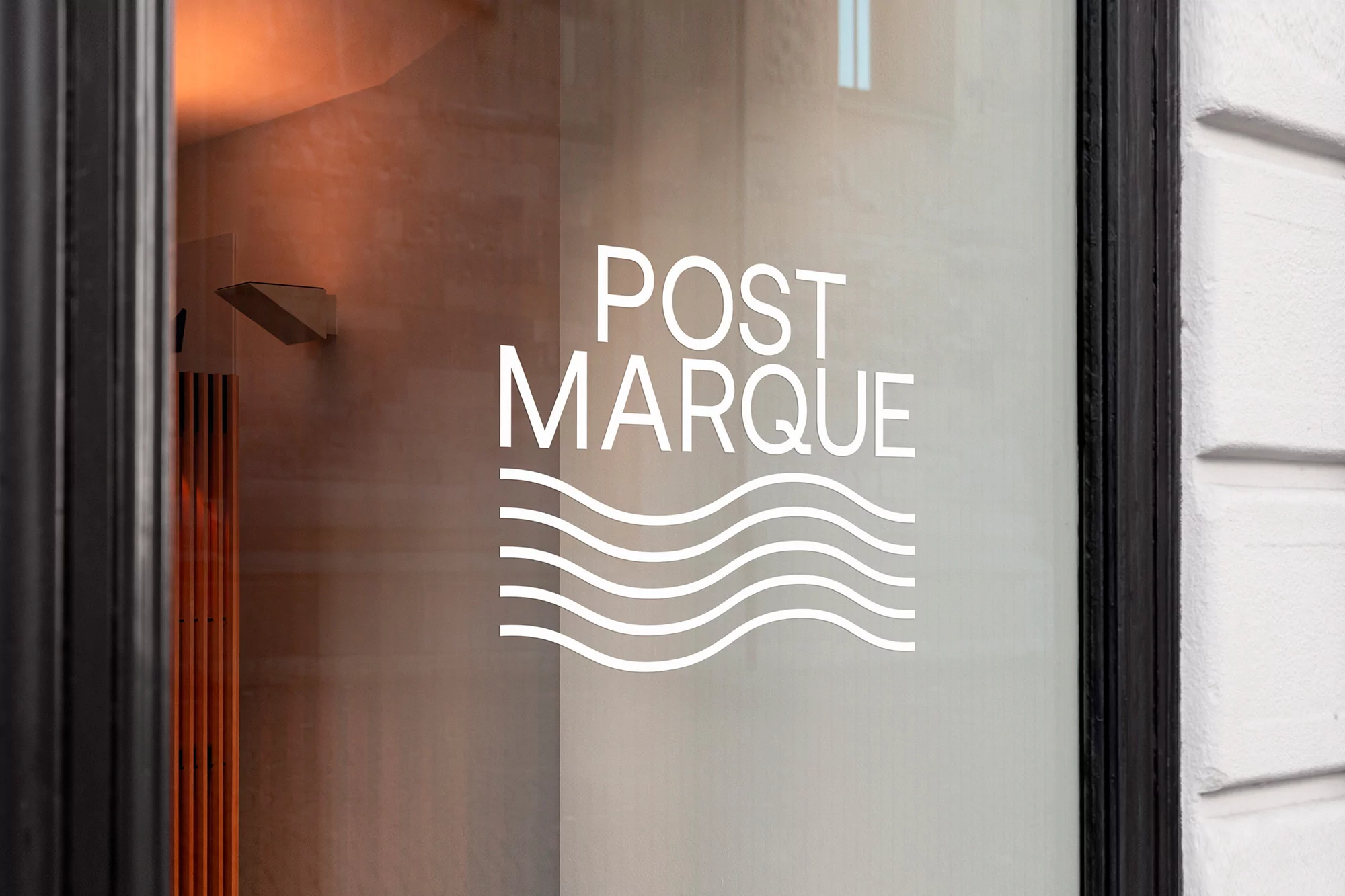 Close-up of a store window with the white text logo “POST MARQUE” and graphic wave lines, seen from the exterior on the street.