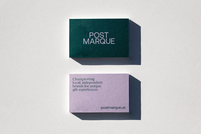Two business cards on a white surface, one green with 'POST MARQUE' and one lavender with company information and website.