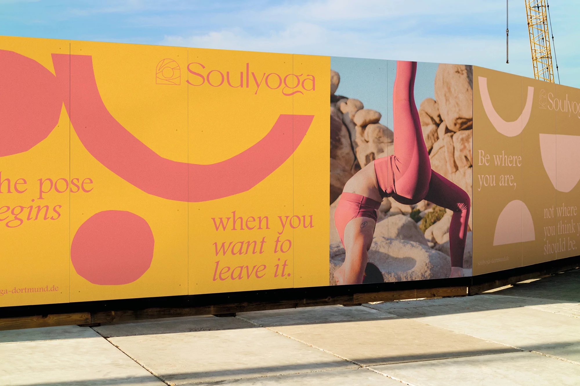 Yoga advertisement on an outdoor wall: a woman is photographed in a yoga pose against a desert landscape, with text and graphic elements.