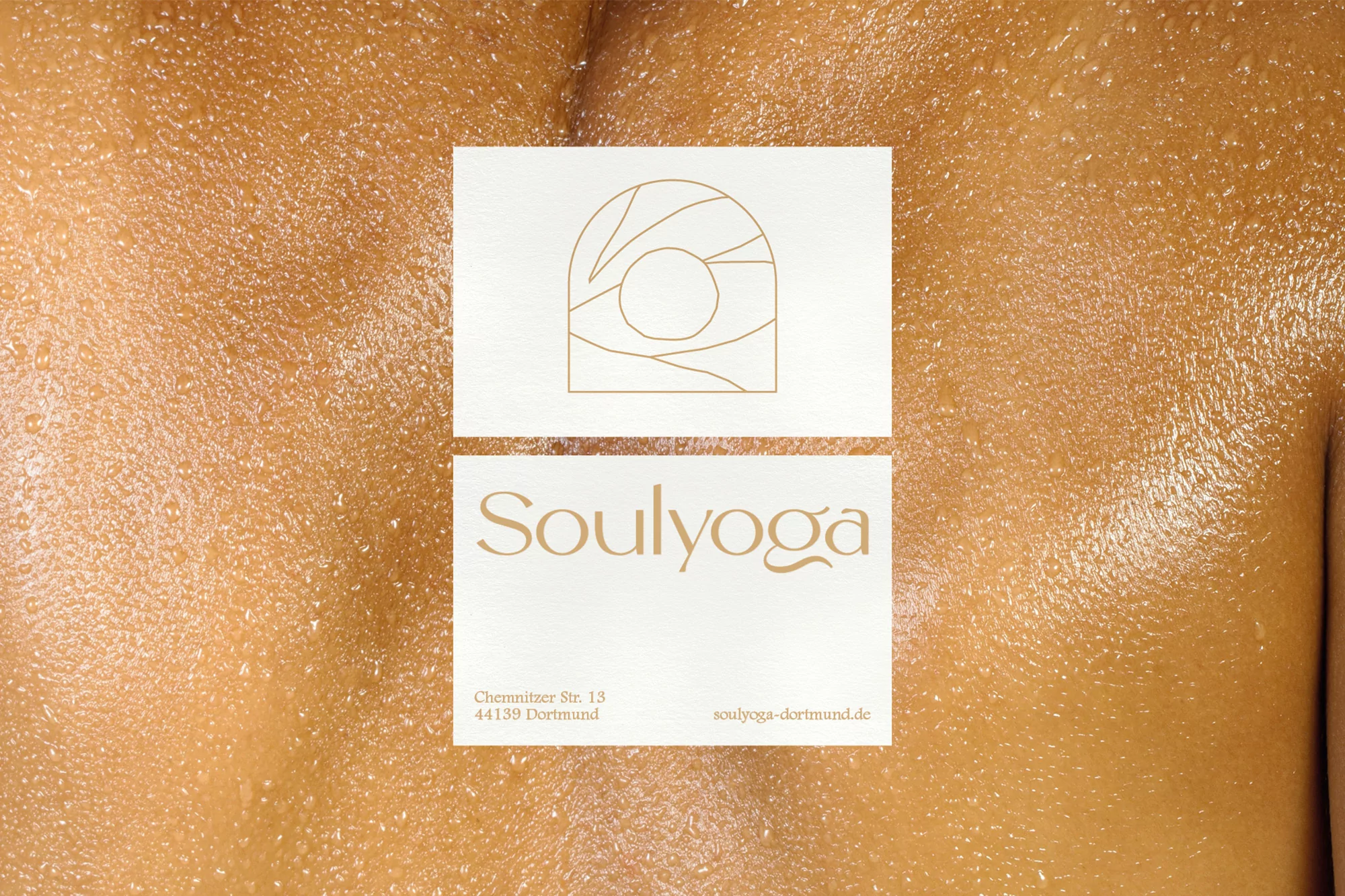 Close-up of a person's glistening skin with two stacked white cards displaying a gold logo and the text 'Soulyoga' and contact details.