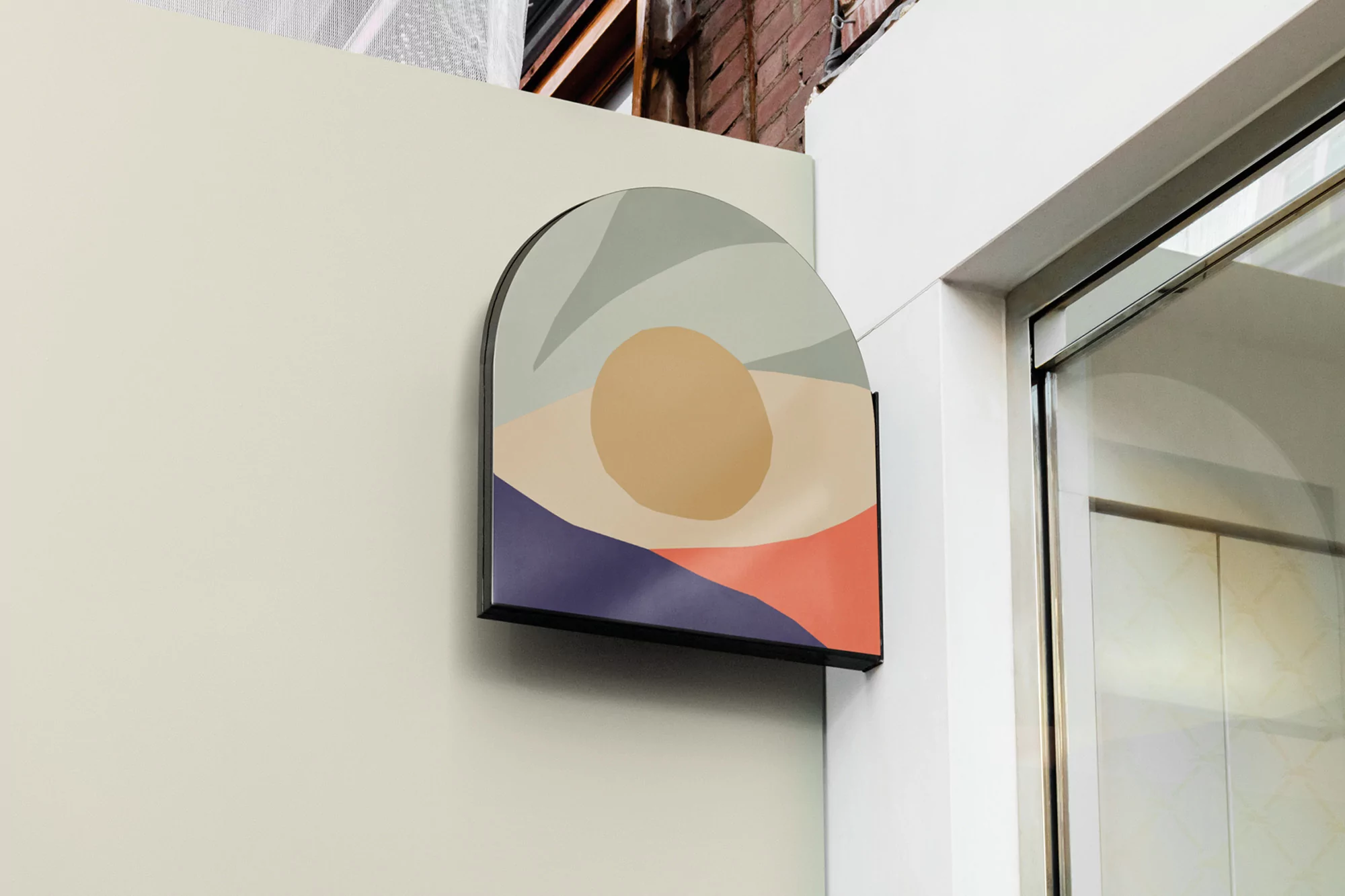 Abstract art on an arched sign, mounted on a building's exterior wall, next to a sliding glass door and red brick building corner.