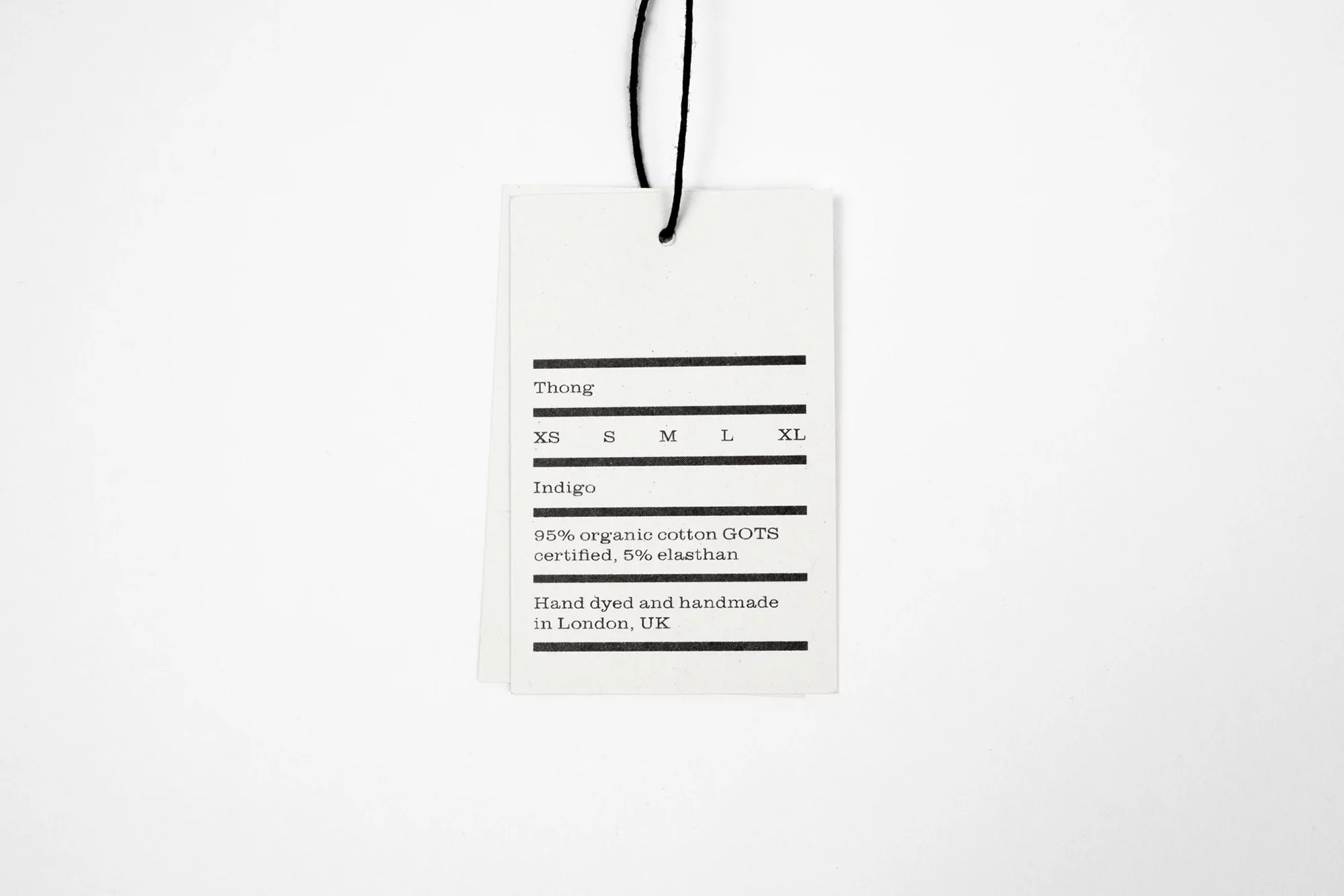 Close-up product shot of a white tag with black string and black text displaying product information on a white background.