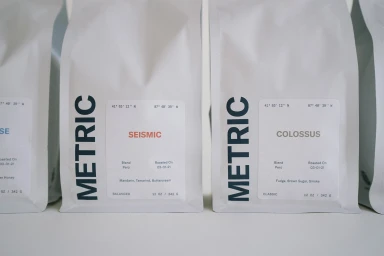 Close-up shot of white coffee bags featuring minimalist typography and labels against a plain background