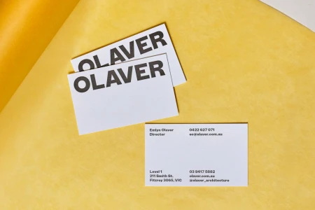 White business cards featuring OLAVER typography arranged on a textured yellow paper background