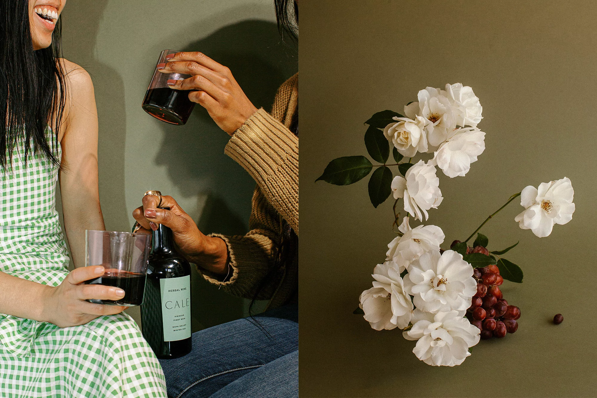 Two women share wine with floral arrangement and green backdrop. One woman wears a green dress, the other a beige sweater and jeans.