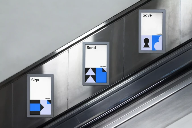 Three DocuSign posters aligned along a gray escalator, displaying 'Sign', 'Send', and 'Save' messages with geometric designs.