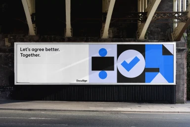 DocuSign billboard displaying brand identity typography and geometric blue and black shapes under a bridge