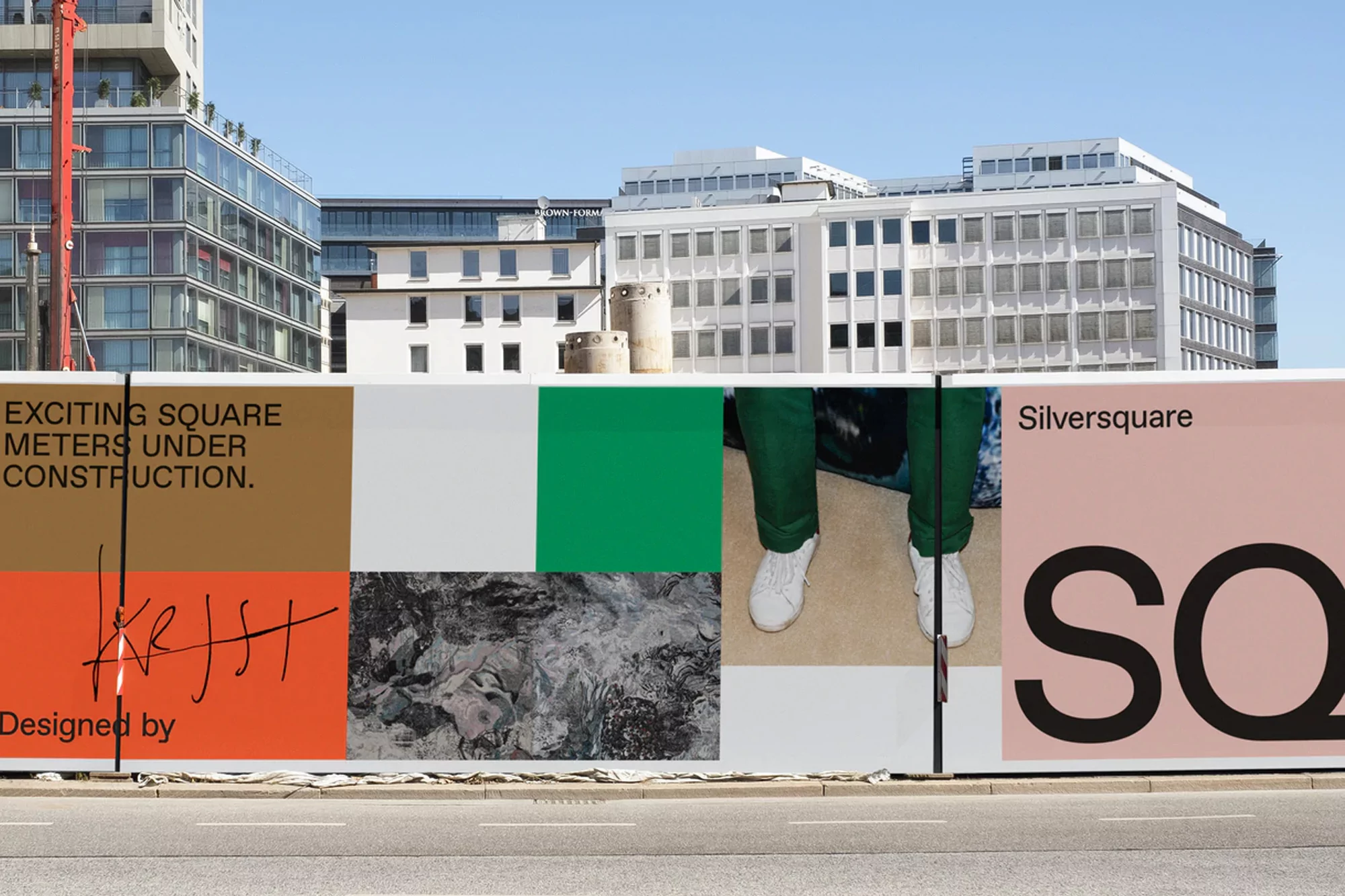 Urban construction site barrier wall with advertising and pedestrian photo in daylight with commercial buildings in background.