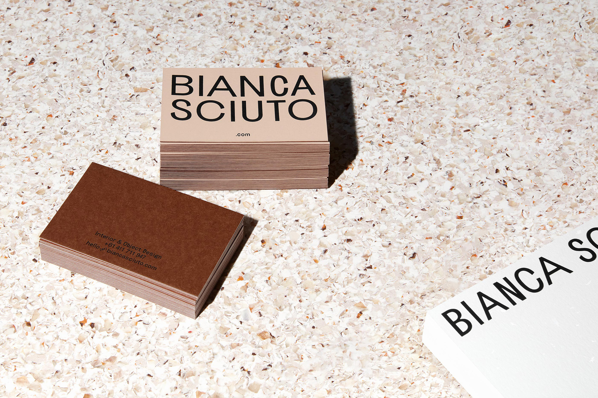Two stacks of business cards and one loose card are displayed on a speckled light-colored surface.