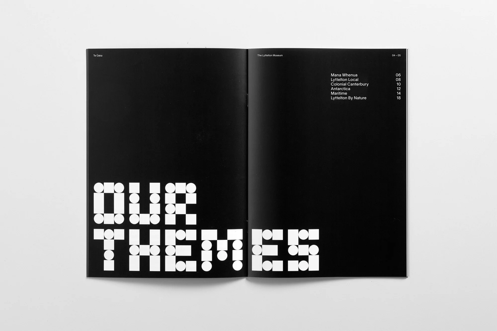 Open book shows 'Our Themes' in large geometric text on the left page, with text content and page numbers on the right page.