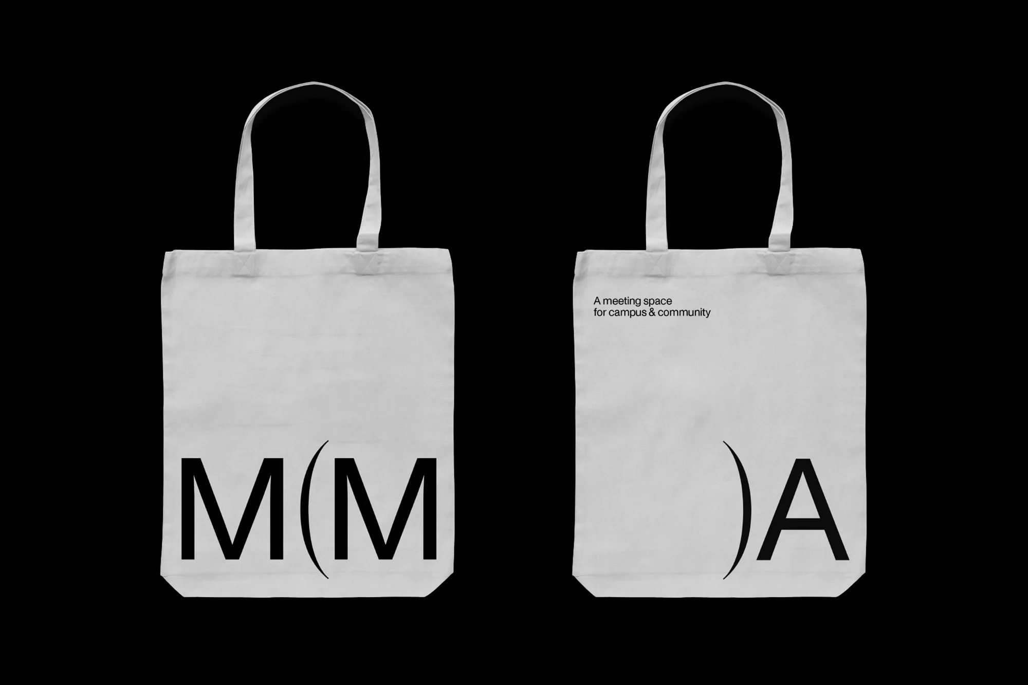 Two white tote bags, displayed against a black background, feature the graphic letters 'M(M' on one and ')A' on the other.