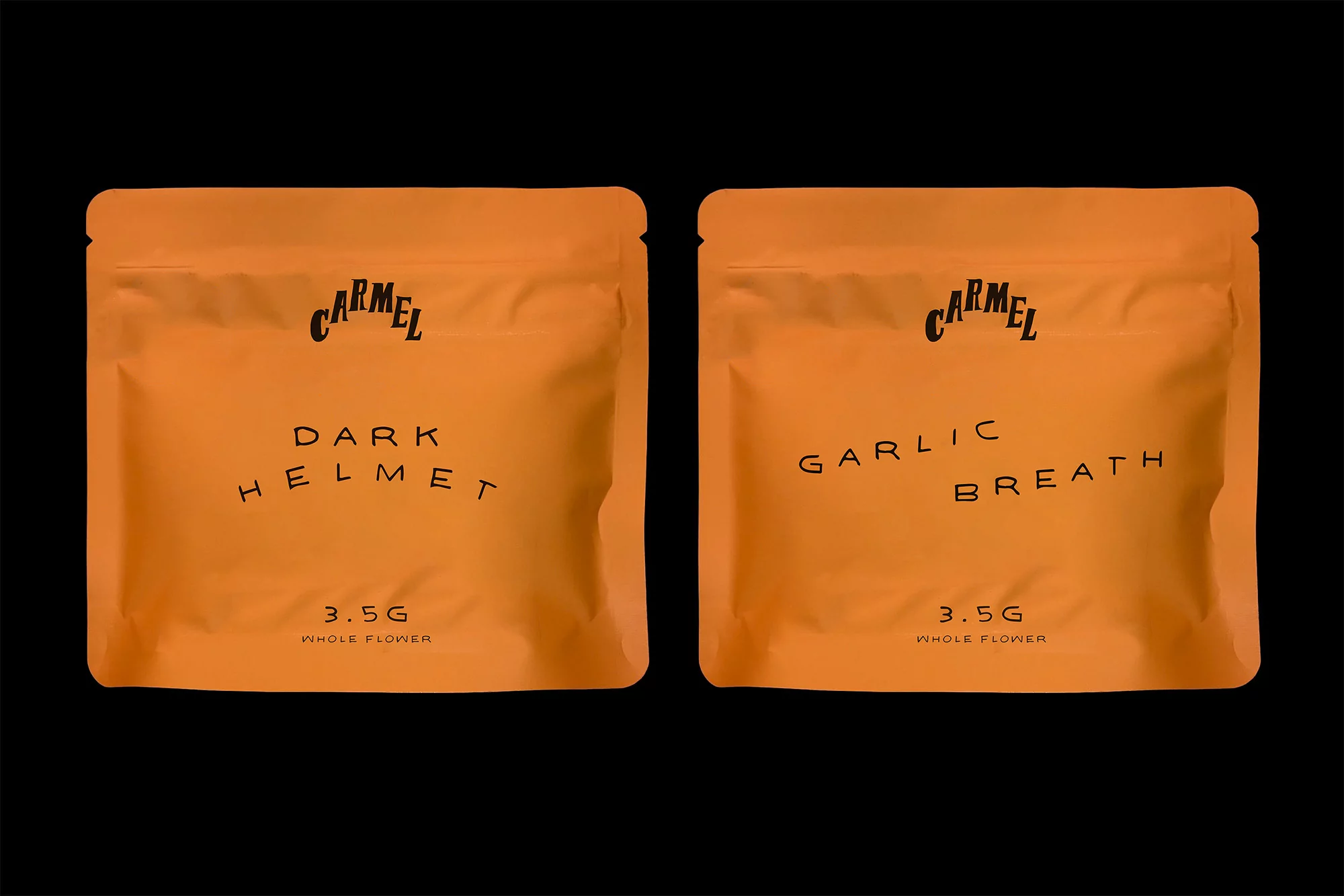 Two orange sealed bags with black text, labeled 'Carmel Dark Helmet' and 'Carmel Garlic Breath,' displayed against a solid black backdrop.