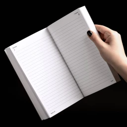 A hand turning the pages of an open lined planner diary against a stark black background.