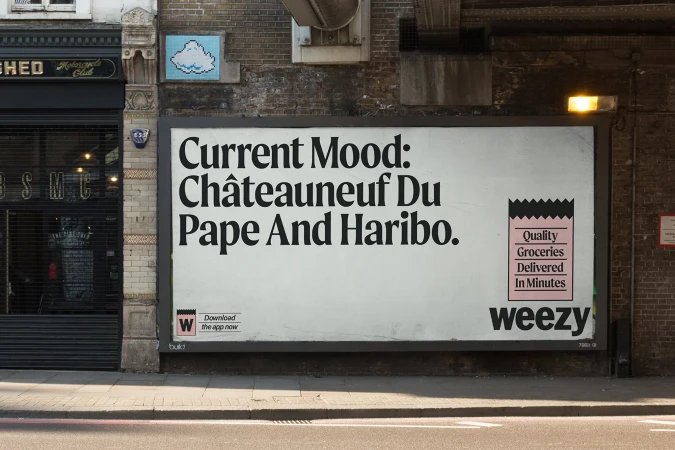 Outdoor billboard with a Weeezy ad promoting quality groceries delivered quickly, featuring bold typography and a grocery bag graphic.