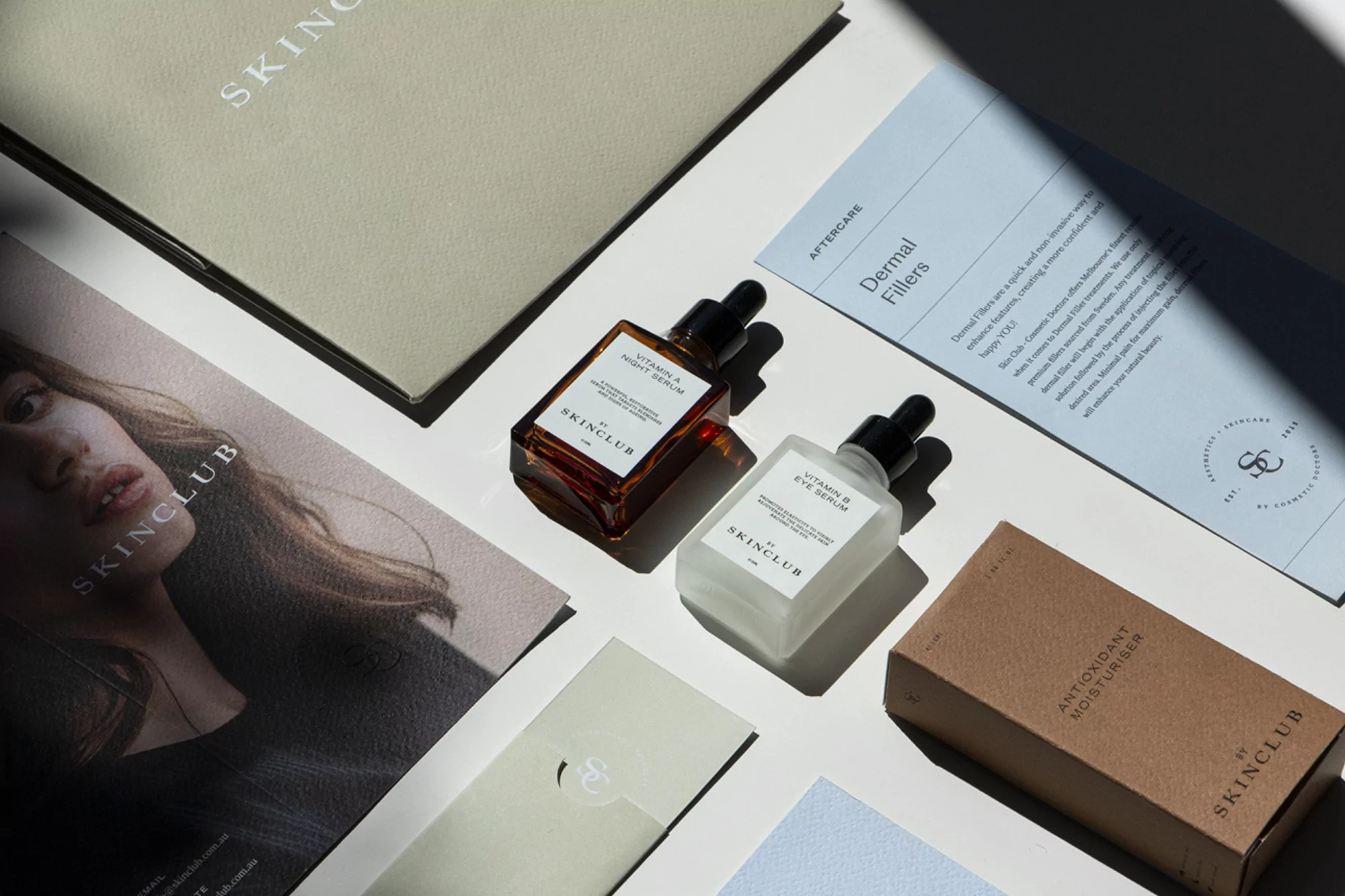Studio shot of Skinclub skincare products, including Vitamin A Night Serum and Vitamin B Eye Serum, next to product brochures and boxes.