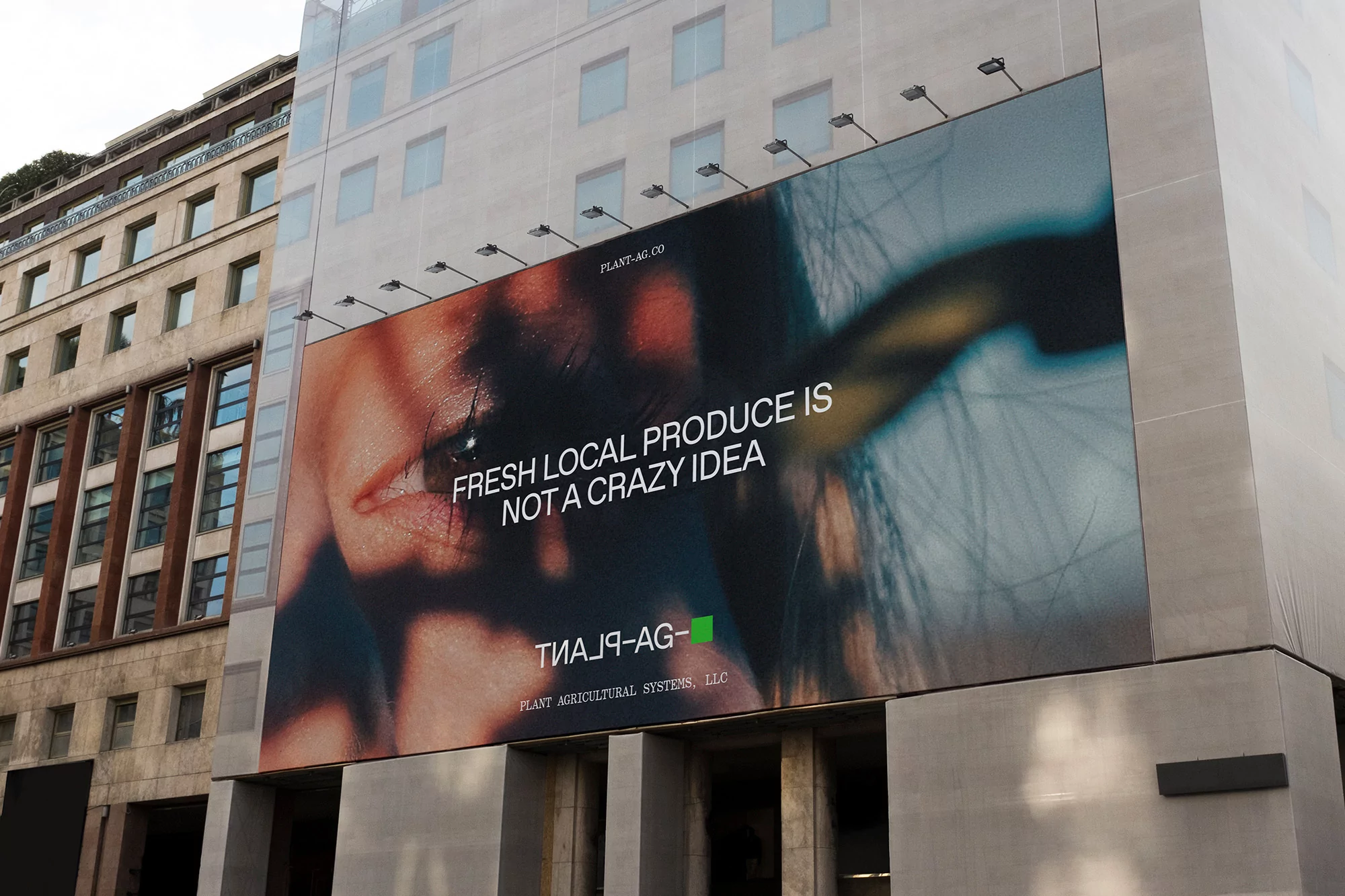 Billboard on the side of a building displays a close-up of a person's face and text promoting local produce, in an urban setting.