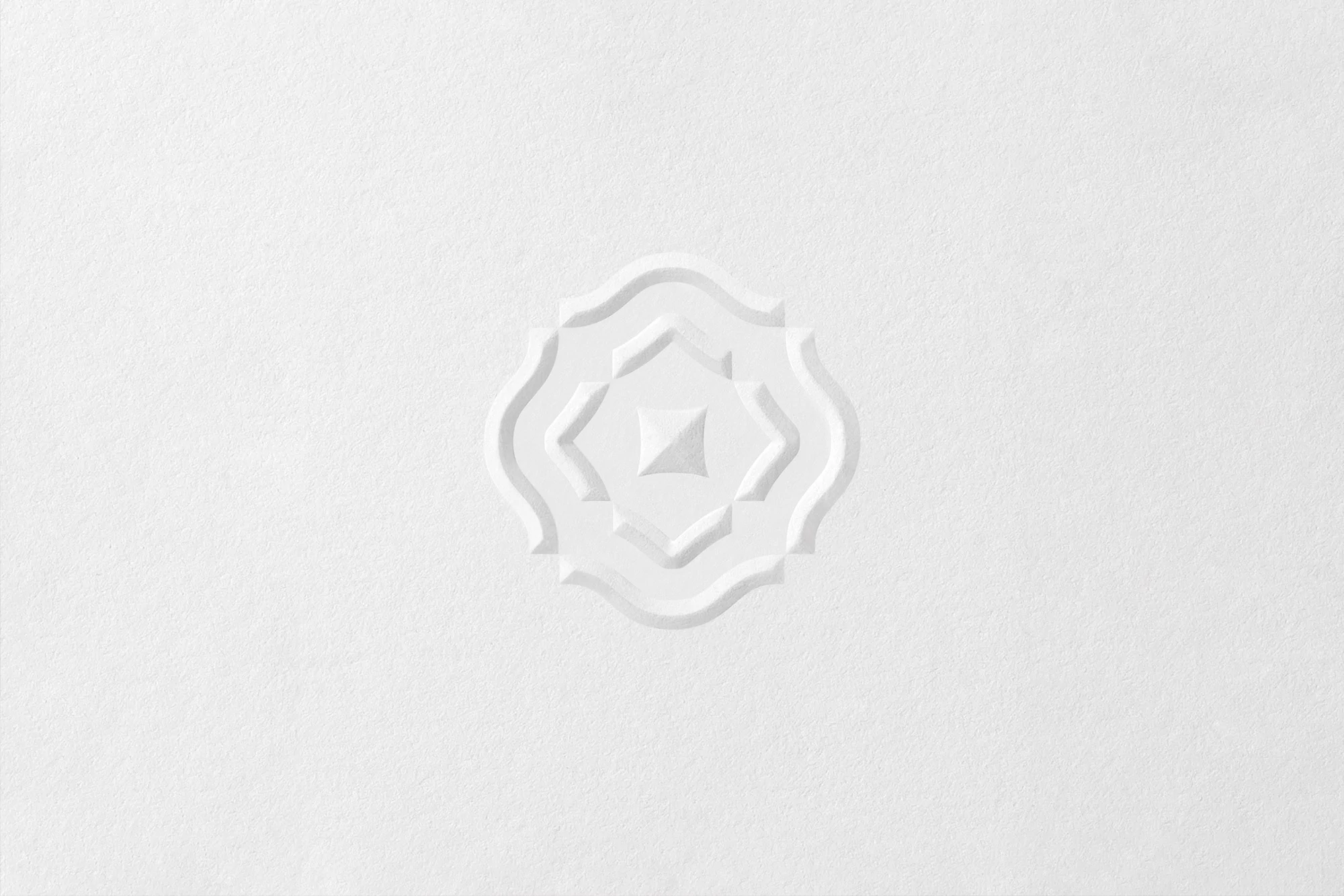 Elegant, all-white embossed paper with a central geometric floral pattern in a minimalist presentation, suitable for subtle backgrounds.