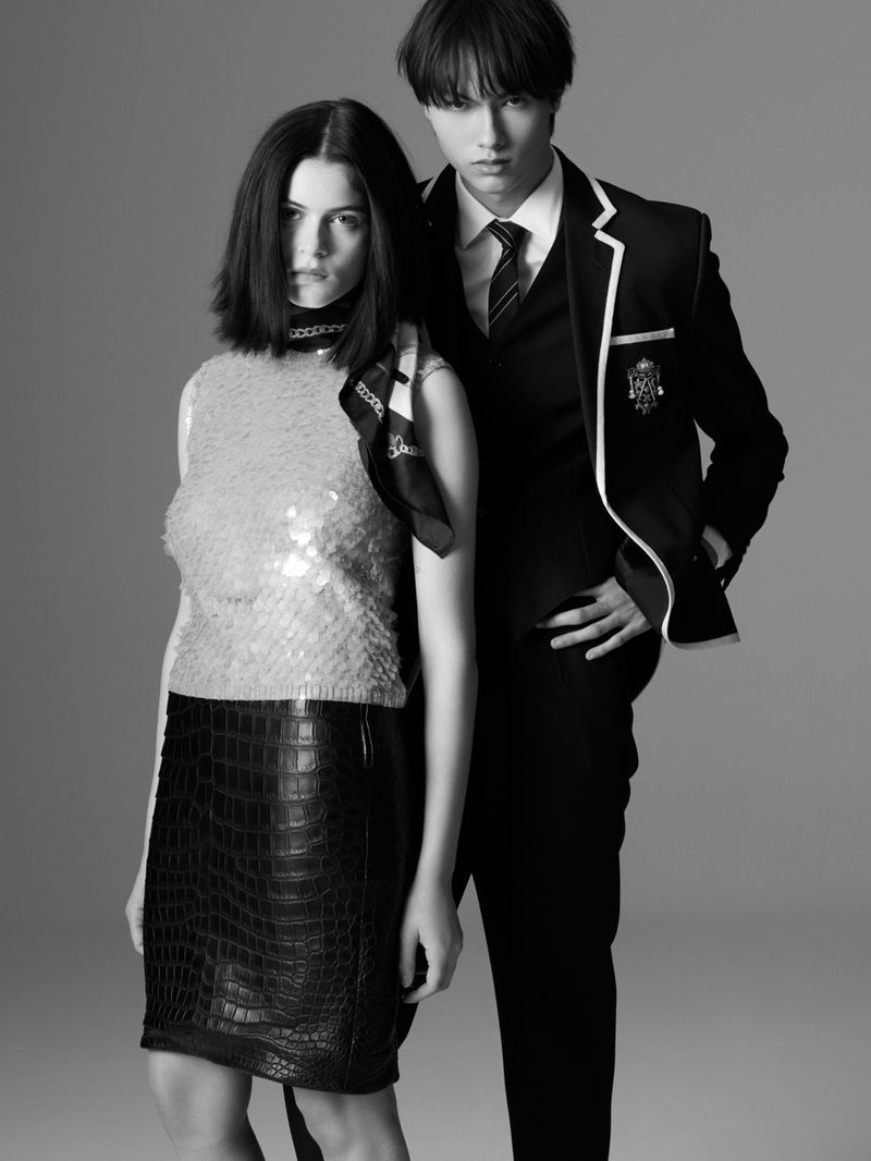 A black and white studio portrait of a woman in a sparkly top and skirt and a man in a suit, both looking directly at the camera.