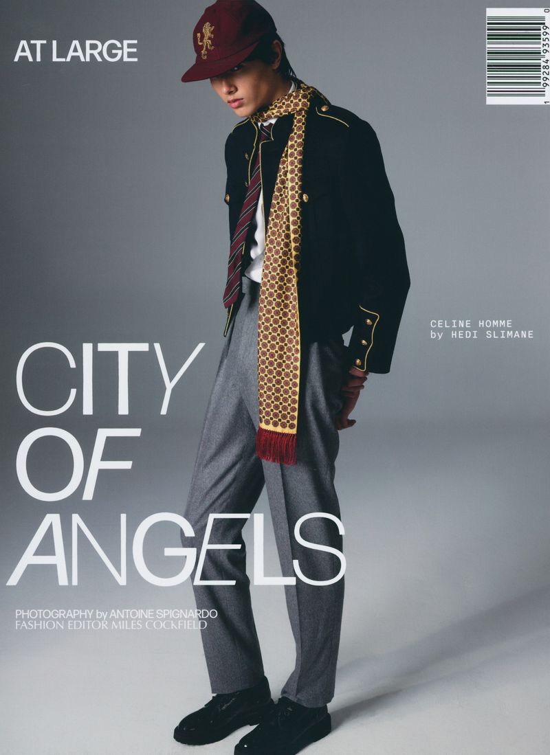 Fashion editorial magazine cover featuring a male model wearing a black jacket, gray trousers, and a patterned scarf and cap.