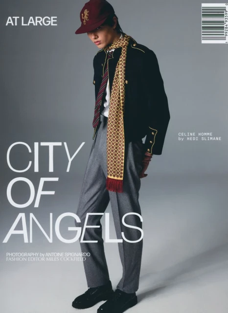 Fashion editorial magazine cover featuring a male model wearing a black jacket, gray trousers, and a patterned scarf and cap.