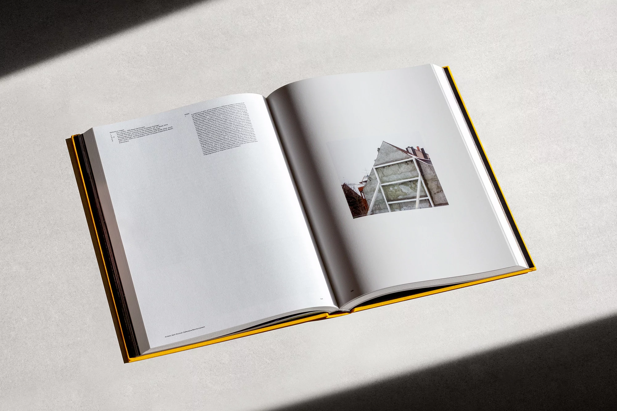 Open book with yellow cover featuring an image of a building's facade, presented on a light surface with a subtle shadow.