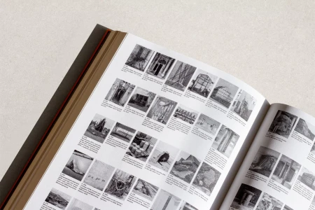 An open monograph book displaying black-and-white architectural photographs and sculpture documentation on paper pages.
