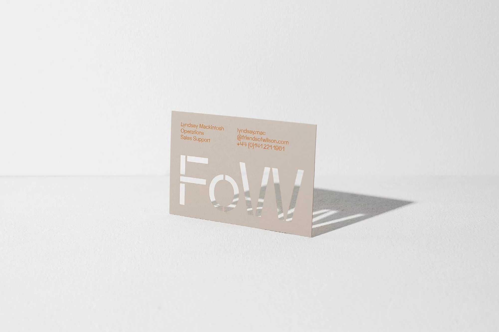 Close-up of a business card on a white surface, featuring company contact information and a modern cutout logo for branding.