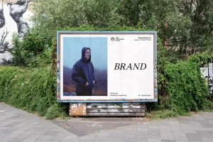 Outdoor billboard featuring branding for Den Nationale Scene with a man in a dark hooded jacket against a misty landscape.