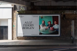 Large billboard under a concrete bridge featuring a poster for Den Nationale Scene with the text Alle Tiders Bergen