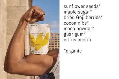 Muscular arm holding a Holos food pouch against a clear sky, with ingredient text list on the right side.