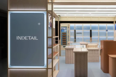 Interior view of the InDetail retail showroom featuring wooden shelving fixtures, display counters, and soft blue and neutral tones.