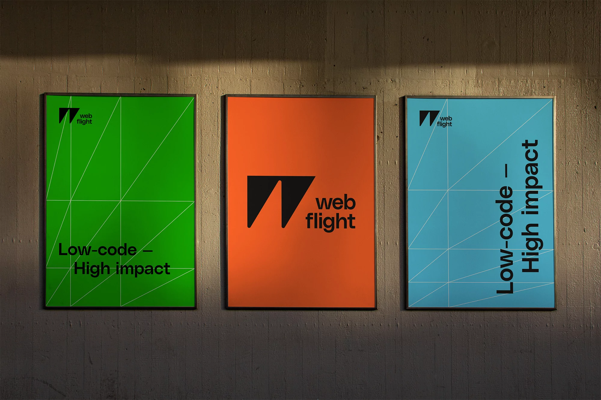 Three framed posters displaying the web flight logo and the text 'Low-code - High impact' are mounted on a concrete wall.