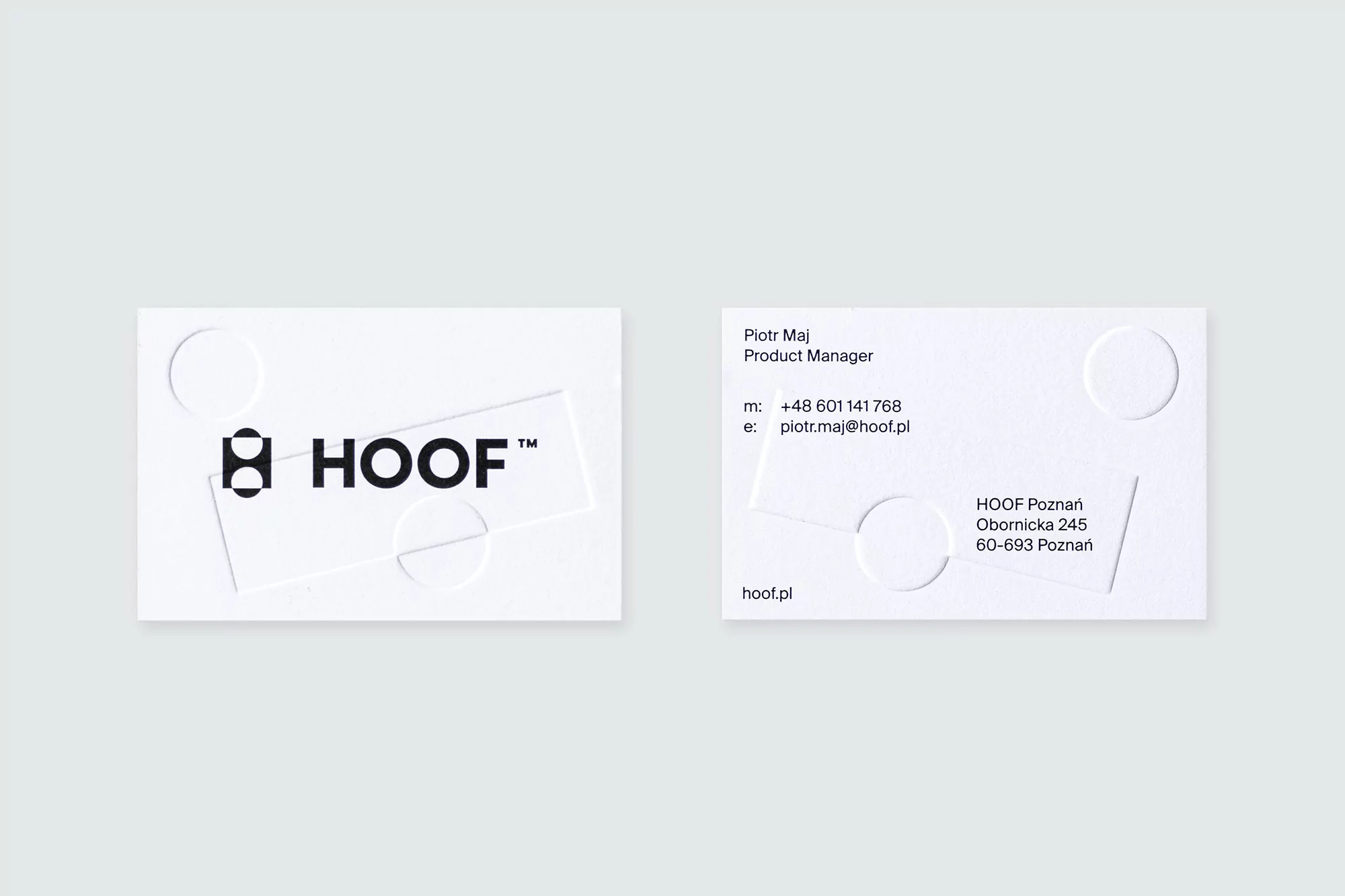Two white business cards featuring black text and logo, one with contact information, circles and lines design; plain background.